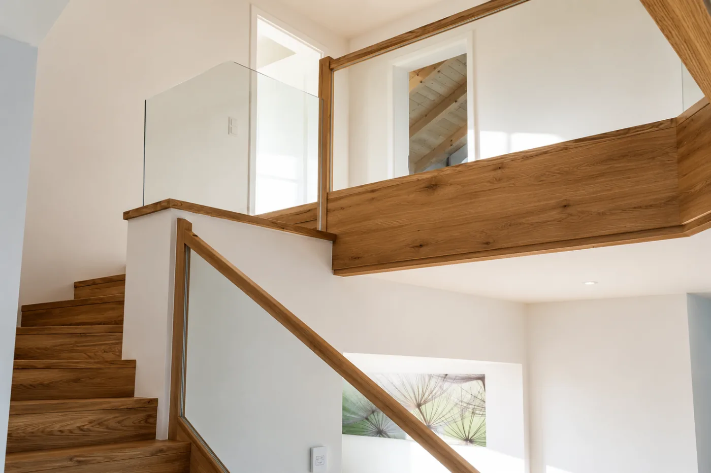 Holztreppe mit Glasgeländer und Galerie